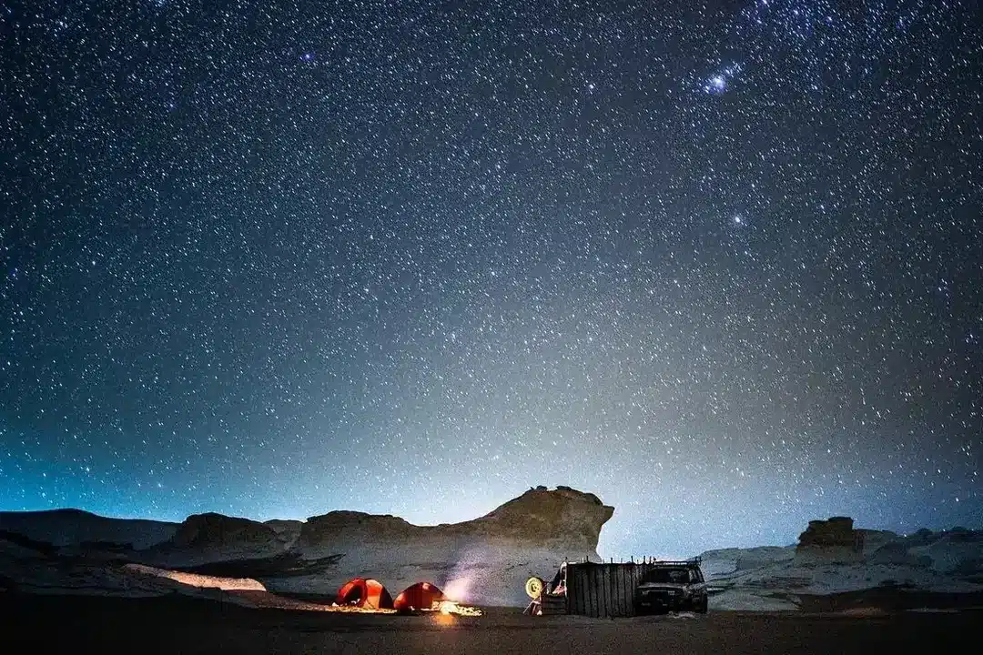 Bedouin-style desert camp and 4x4 vehicle beneath stars in White Desert Egypt